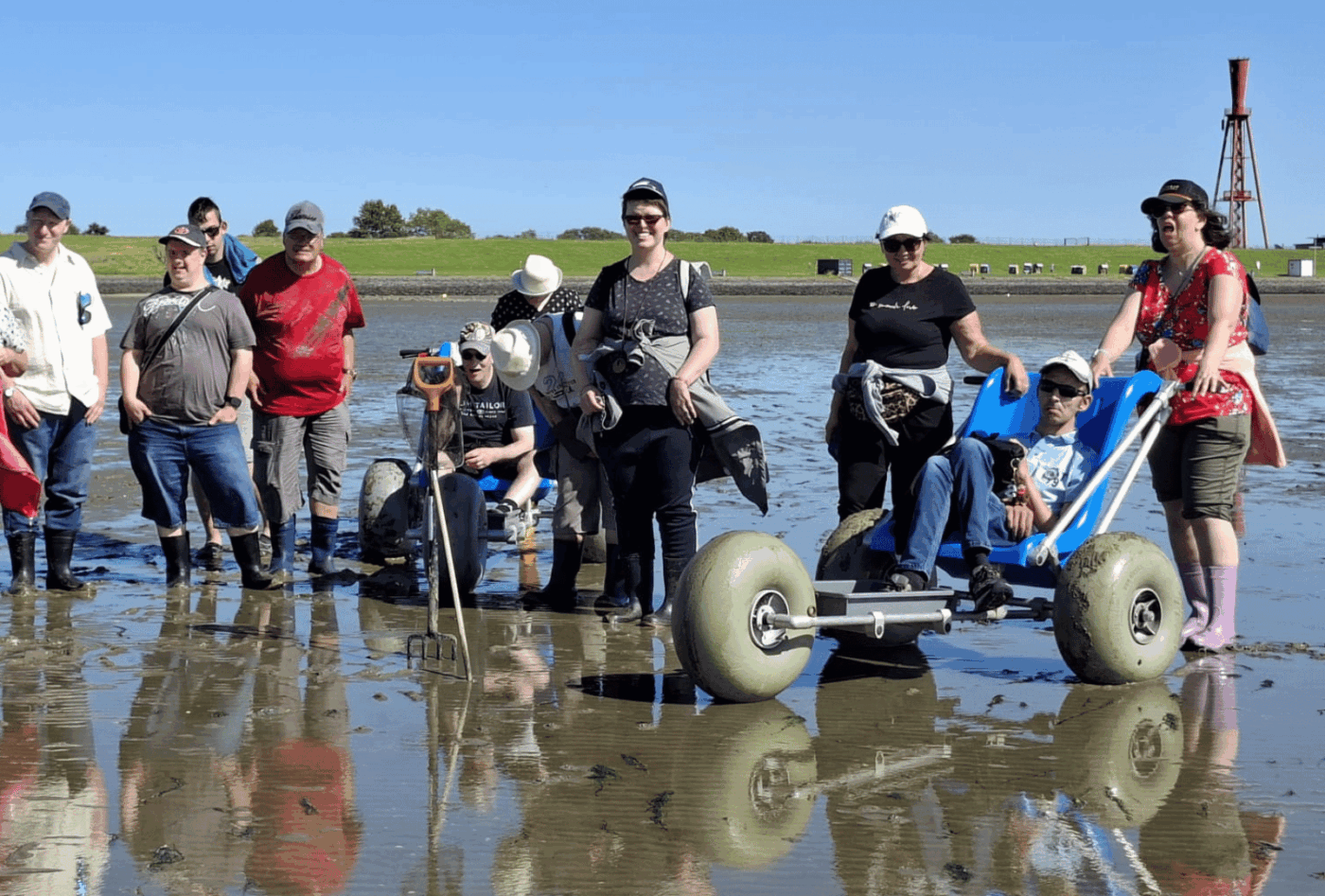 Reisegruppe aus dem Bereich Wohnen bei einer Wattwanderung an der Nordsee mit zwei geländegängigen Wattrollstühlen.